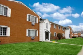 Red brick apartment buildings with blue clouded sky and green grass