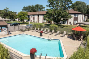 a swimming pool with chairs around it in front of a building