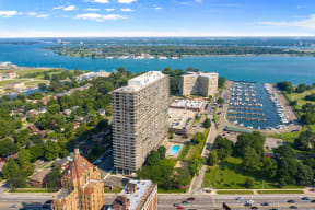 Exterior of the Jefferson. The building is on the Detroit River. There is green grass around the building. The Jefferson stands 30 stories tall. The sun is shining and there are blue skies.