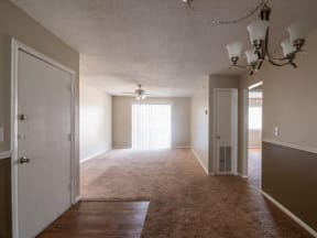 Living and dinning area with plush carpeting, and light neutral walls and a silver chandler.