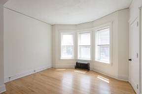 an empty room with a wood floor and three windows