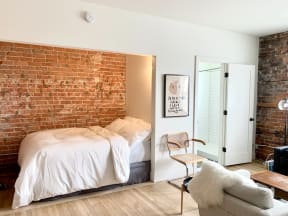 a brick wall in a bedroom with a bed and a couch