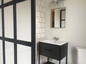 a bathroom with a black and white tiled wall and a white sink with a mirror above