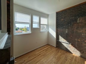 an empty room with three windows and a brick wall