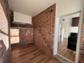a bedroom with a brick wall and hardwood floors