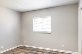 an empty room with a window and a wooden floor