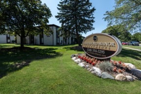 a sign in front of a grassy area with trees in the background