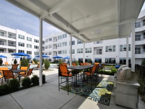a patio with a table and chairs and a grill