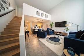 a living room with couches and chairs and a staircase