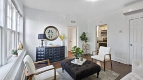 a living room with white walls and a black ottoman
