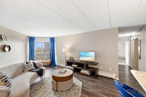 A living room with a white couch, a coffee table, and a television.