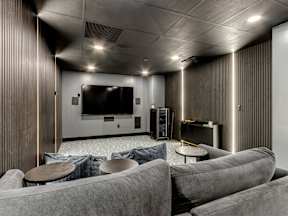 A modern living room with grey couches and a flat screen TV.
