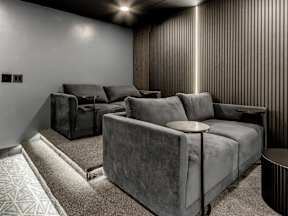 A grey couch and chair in a room with a carpeted floor.