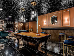 A pool table is in the middle of a room with a black ceiling.
