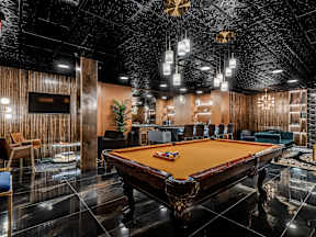 A pool table is in the middle of a room with a black ceiling.