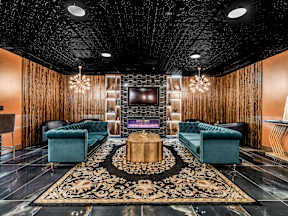 A living room with a dark ceiling and a large rug in the center.