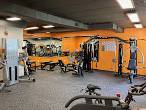 A gym with orange walls and various exercise equipment.