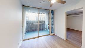 A room with a ceiling fan and sliding glass doors.