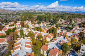 an aerial view of a neighborhood with orange roofs and a green hillside in the background