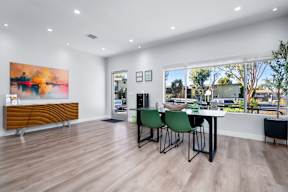 A room with a wooden floor, a table with chairs, and a large painting on the wall.