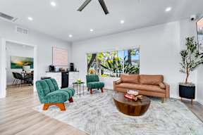 A living room with a brown couch, green chairs, and a wooden coffee table.