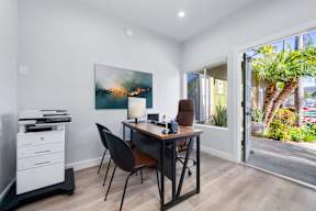 A room with a desk, chair, and a painting on the wall.