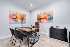 A room with a table and chairs and two paintings on the wall.
