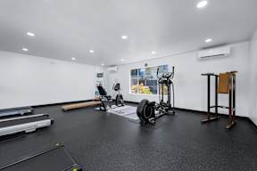 A gym with a variety of equipment including a treadmill, weights, and a bench press.