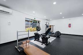 A gym with a variety of equipment including a treadmill, weights, and a bench press.