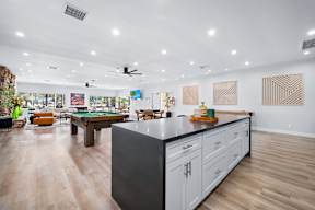 A modern kitchen with a pool table in the middle.