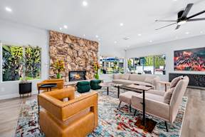 A living room with a stone fireplace and a painting of a forest fire.