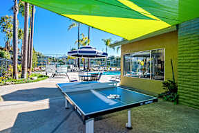 A ping pong table is in the middle of a patio.