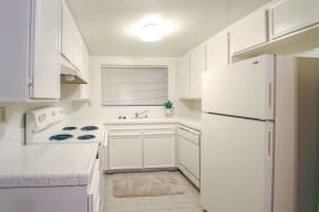 A small kitchen with white cabinets and a refrigerator