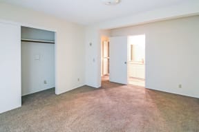 An empty living room with white walls and a door to a bathroom.