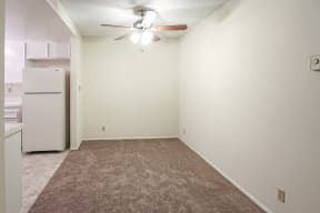 An empty room with a white refrigerator and a ceiling fan.