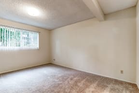 the spacious living room of an empty home with a window