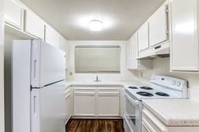 A kitchen with white cabinets and white appliances and a refrigerator.