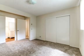 an empty bedroom with white closets and a carpeted floor
