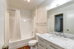 A bathroom with a shower toilet and sink and a mirror.