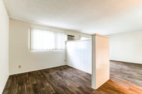 the spacious living room and dining room of an apartment with wood flooring