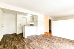 an empty living room and kitchen with a hard wood floor