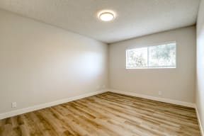 an empty living room with wood flooring and a window