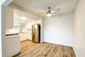 An empty kitchen with white cabinets and a stainless steel refrigerator.