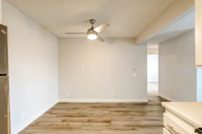 An empty kitchen and living room with a ceiling fan.