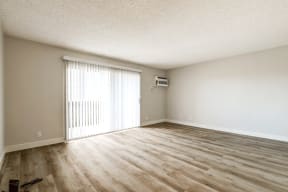 spacious living room with wooden floors and sliding glass door and vertical blinds