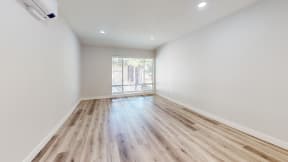 a living room with white walls and wood flooring and a window at Charter Oaks Apartments, California, 91360
