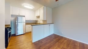 an empty kitchen with white cabinets and a stainless steel refrigerator at Charter Oaks Apartments, California, 91360