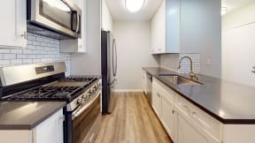 a kitchen with stainless steel appliances and white cabinets at Charter Oaks Apartments, California, 91360