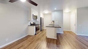 a kitchen with an island and stainless steel appliances and a hard wood floor at Charter Oaks Apartments, California, 91360