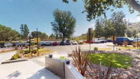 a parking lot with cars parked in it and a grassy area with trees at Charter Oaks Apartments, California, 91360